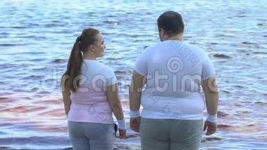 肥胖的女人拥抱她肥胖的男朋友，享受平静的湖景